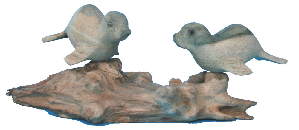 Zwei Seehunde aus Holz auf Treibholz